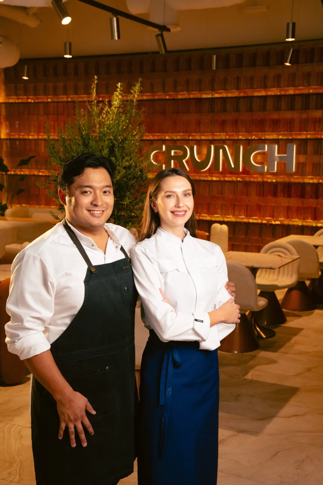 Mukhtar and Anastassiya in their chef whites in front of the CRUNCH sign