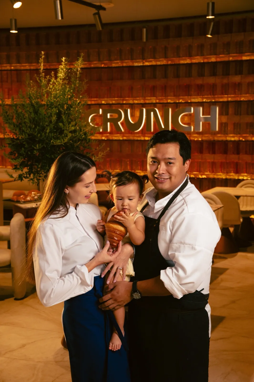 Anastassiya and Mukhtar with their daughter holding a croissant